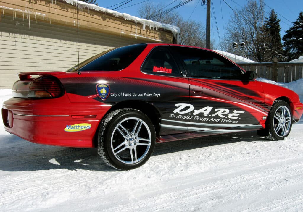 DARE car graphics and custom car wrap in Fond du Lac, WI. Red care with D.A.R.E. swoosh in black across the door.